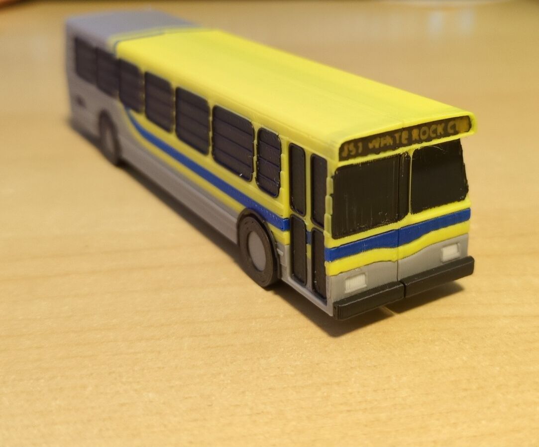 A closer look at the 3d printed bus. It uses the CMBC suburban grey color scheme (Grey body, yellow stripe, blue stripe and another yellow strip going to the roof of the bus. the stripes curves upward towards the end of the bus.)